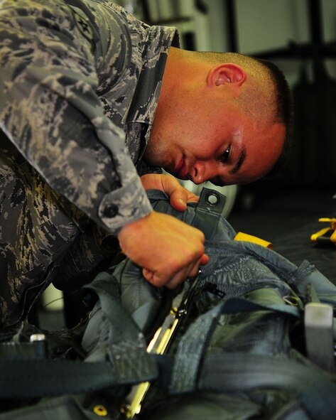 YOKOTA AIR BASE, Japan-- Airman Devin Ballesteros, 374th Operations Support Squadron survival equipment flight, inspects the back of an automatic parachute harness July 2. For safety purposes a parachute is repacked every 180 days. The survival equipment shop repacks approximately six parachutes a week. (U.S. Air Force photo/Airman 1st Class Michael Dillon)