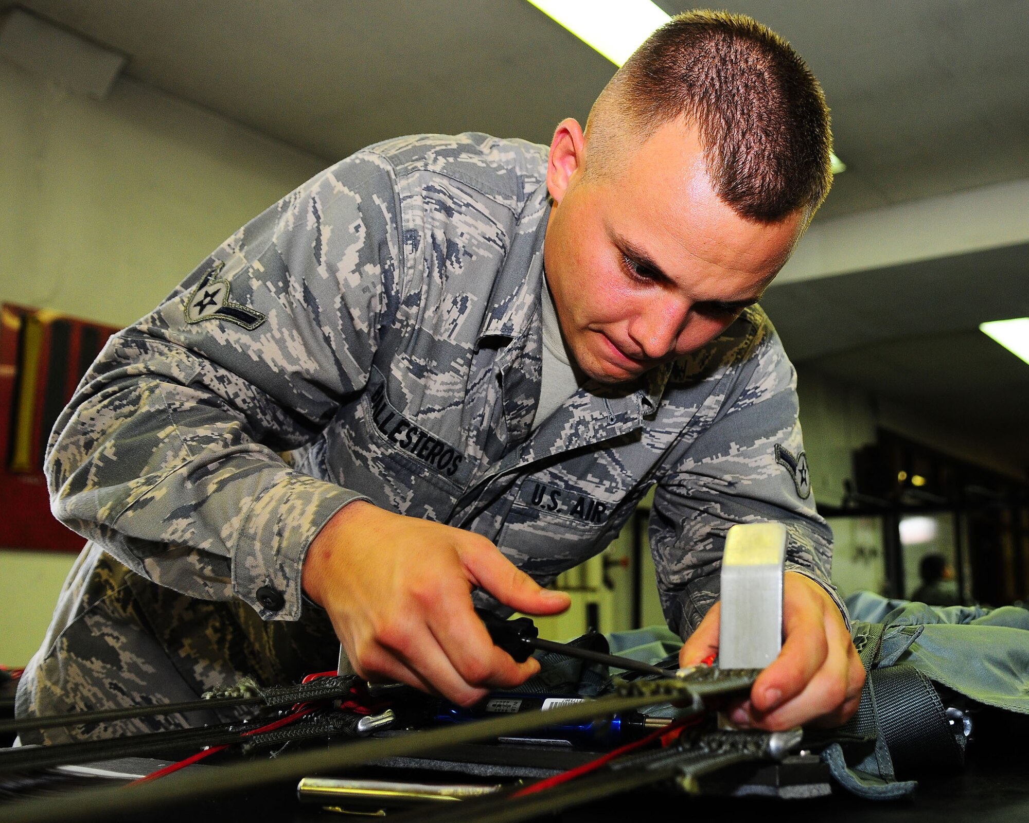 YOKOTA AIR BASE, Japan-- Airman Devin Ballesteros, 374th Operations Support Squadron survival equipment flight, tightens a metal plate on the connector link to ensure that the canopy holds to the harness July 2. For safety purposes a parachute is repacked every 180 days. The survival equipment shop repacks approximately six parachutes a week. (U.S. Air Force photo/Airman 1st Class Michael Dillon)