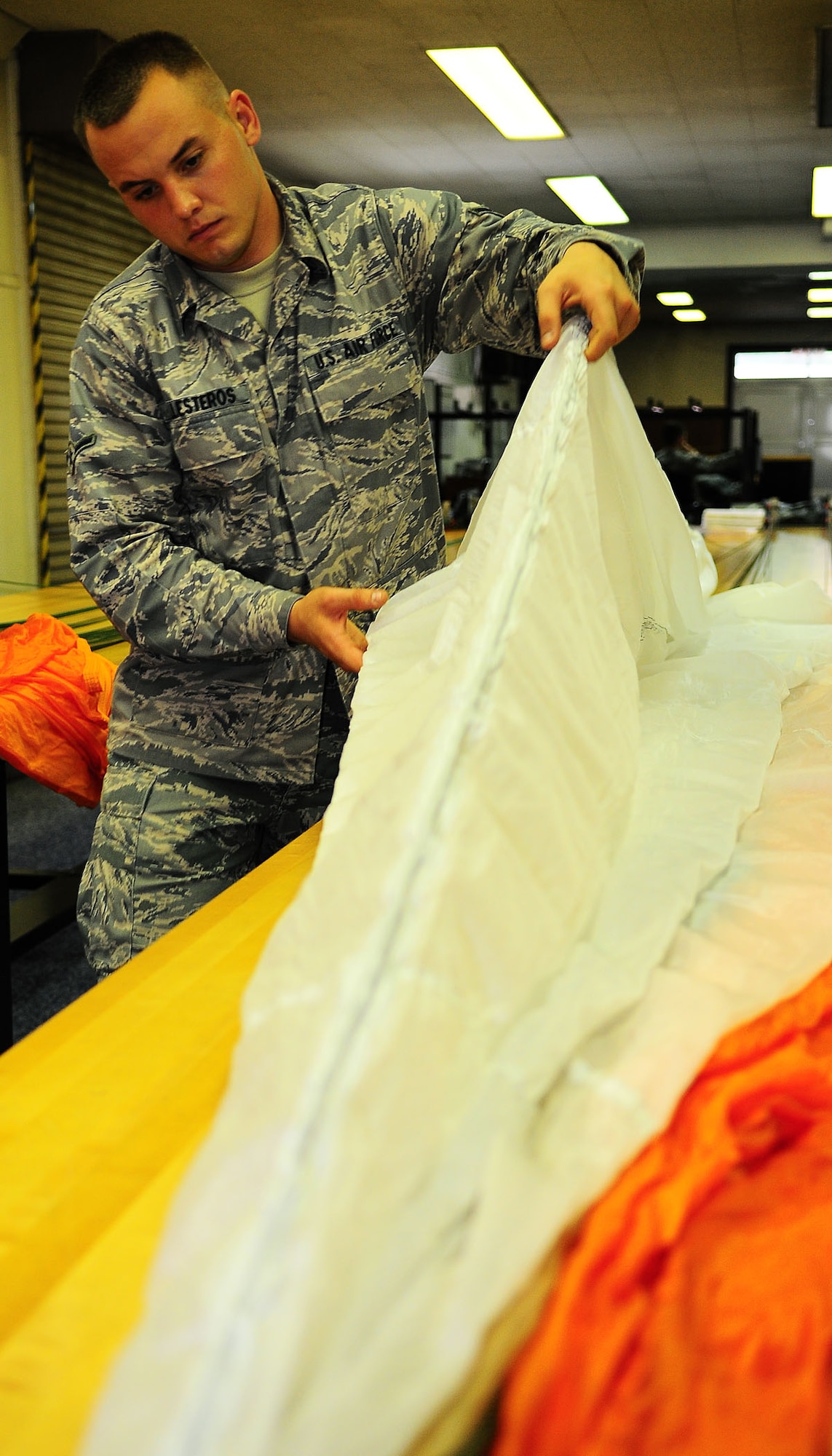 YOKOTA AIR BASE, Japan-- Airman Devin Ballesteros, 374th Operations Support Squadron survival equipment flight, inspects a parachute for any dirt grease or rips July 2. For safety purposes a parachute is repacked every 180 days. The survival equipment shop repacks approximately six parachutes a week. (U.S. Air Force photo/Airman 1st Class Michael Dillon) 