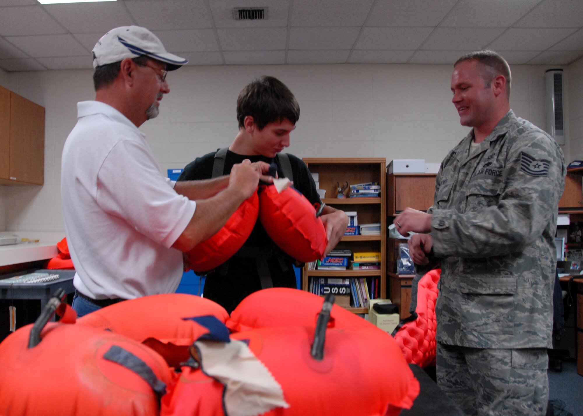 Air Force Reserve Tech Sgt. Christiaan Becker, 919th Operations Support Squadron Aircrew Flight Equipment, instructs visitors from Walton High School’s Air Force Junior ROTC unit on how to inflate a life vest June 30 as part of Junior ROTC Day at Duke Field.  Four other high school Junior ROTC programs also visited getting tours of life support, maintenance, and even a short flight on a 919th Special Operations Wing MC-130E aircraft.  Approximately 110 students toured the base.  (U.S. Air Force photo/ Staff Sgt. Samuel King Jr.)