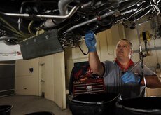 Danny Page drains the fuel filter on a C-17 engine in the test cell here June 18. The fuel filter must be drained before it can be inspected for contaminates. The all-civilian engine shop installs, inspects and repairs five to six engines a month. Mr. Page is an aviation maintenance technician with United Airlines. (U.S. Air Force photo/Senior Airman Katie Gieratz)