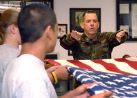 Travis Honor Guardsman Master Sergeant Paul McCullough instructs Air Force JROTC (Junior Reserve Officer Training Corps) Cadets on how to perform a six man flag folding ceremony.  The Cadets are part of the JROTC program at Del Campo High School in Fair Oaks, California. (U.S. Air Force photo by Civ/Nan Wylie)