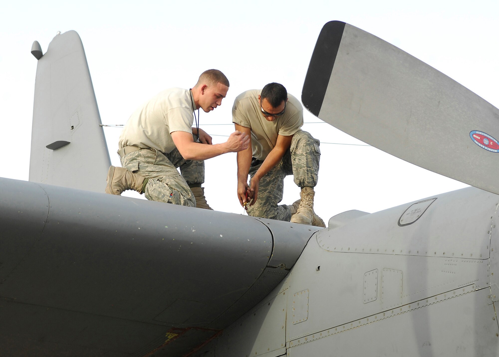 BAGRAM AIR FIELD, Afghanistan - Technical Sergeant Jose Rodriguez (right) assists Staff Sgt. Andres Jaramillo in securing bolts during a function check on the  EC-130 Compass Call. Both are members of the 41st Expeditionary Aircraft Maintenance Unit and are deployed out of Davis-Monthan Air Force Base, Ariz. (U.S. Air Force photo/Senior Airman Felicia Juenke)