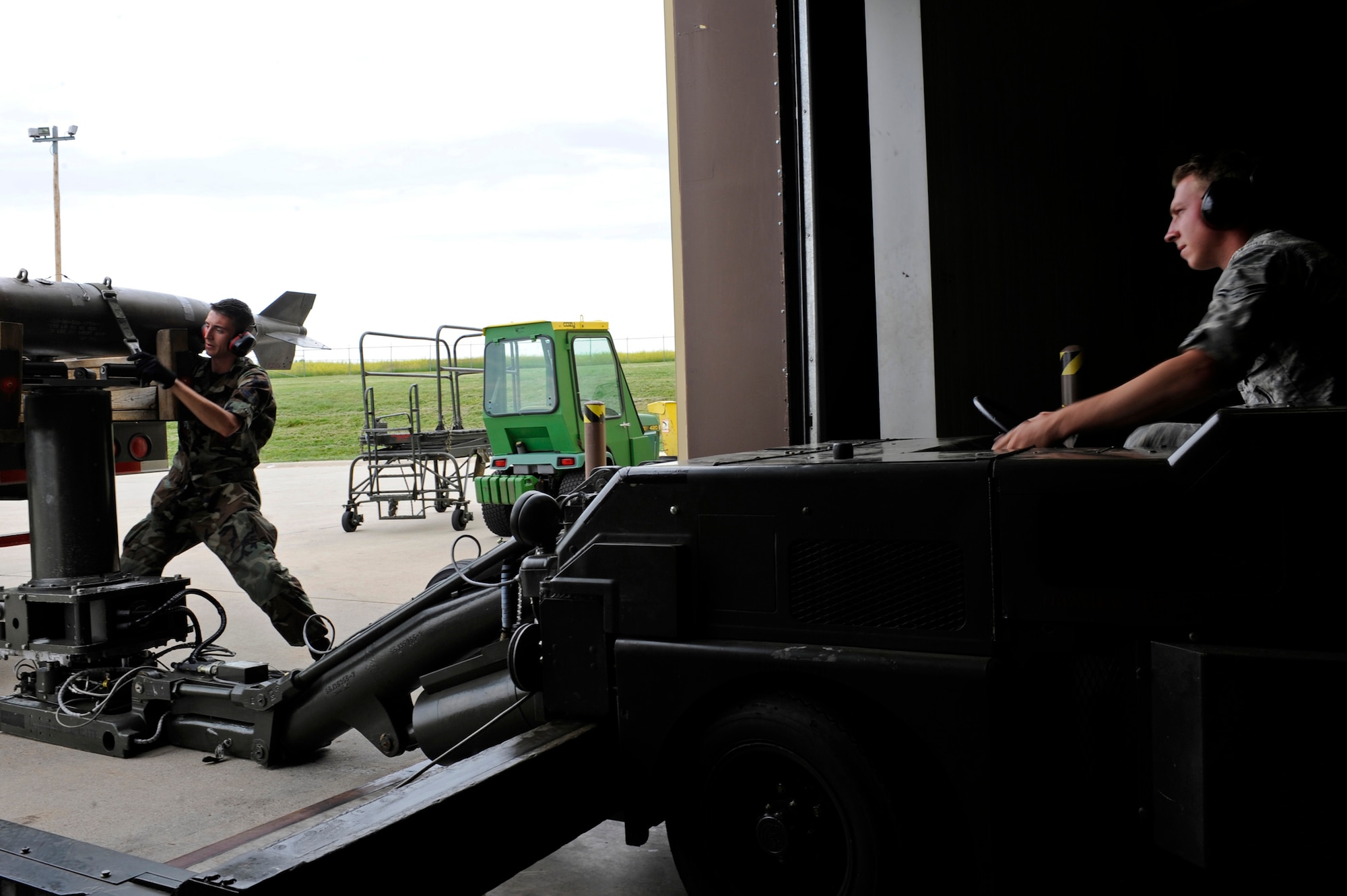 (Left)  Airman 1st Class Anthony Floyd, 28th Aircraft Maintenance Squadron weapons load crew member, prepares a MK-82 bomb to be placed on a MHU-83 jammer operated by Airman 1st Class Robert Weick, 28 AMXS weapons load crew member, here, July 1. The quarterly competition will feature two, four-man teams representing the 34th and 37th Bomb Squadrons July 7. (U.S. Air Force photo/Airman 1st Class Matthew Flynn)