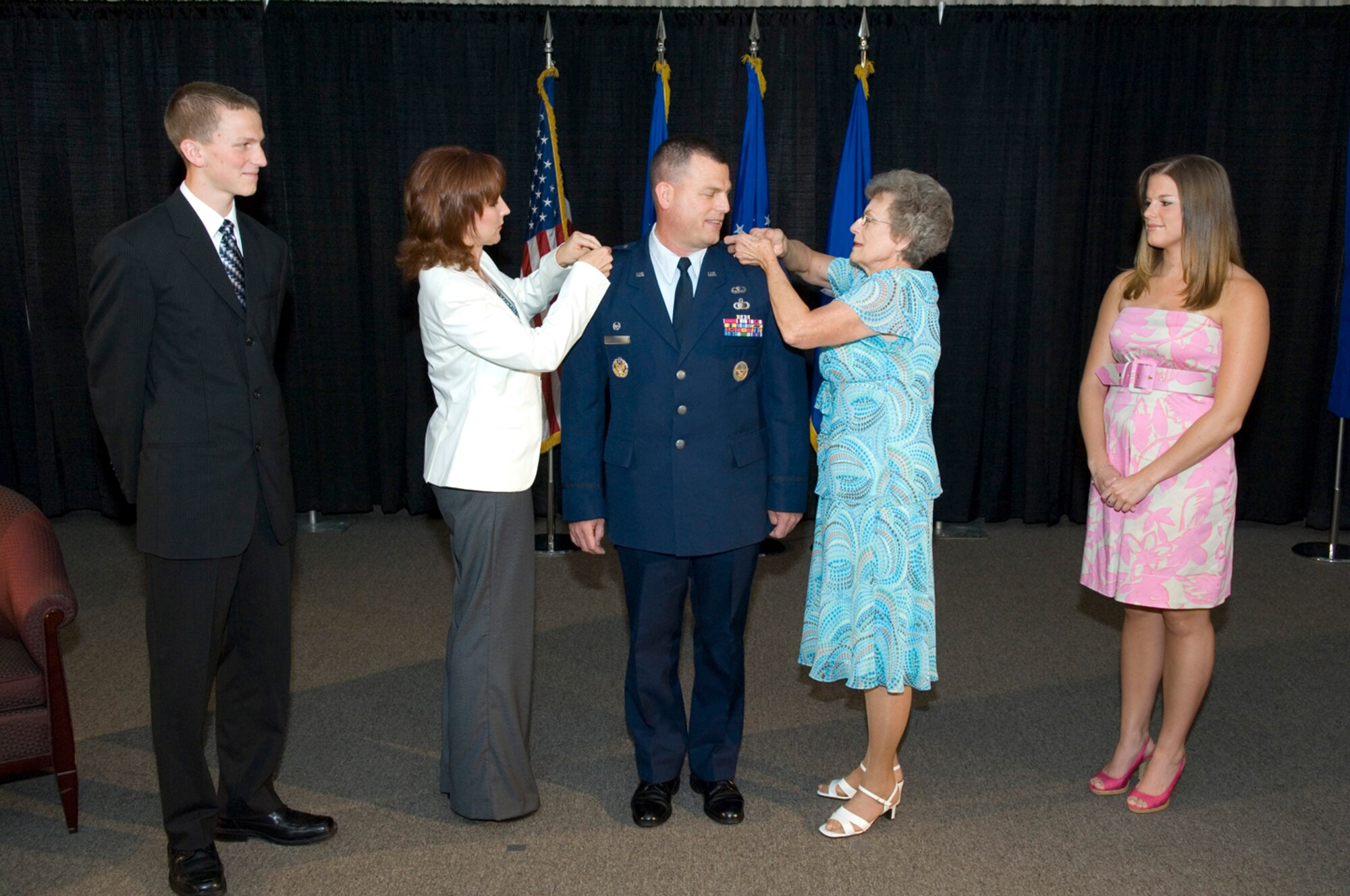 Brig. Gen. Dwyer Dennis, commander of the 551st Electronic Systems Wing, pauses while his wife, Tammy, (left) and mother, Louanna Sturm, pin on his new rank during a promotion ceremony July 2 at the Hanscom Conference Center. Two of the general’s four children, Derek and Alison, also took part in the ceremony.  (USAF Photo by Rick Berry)