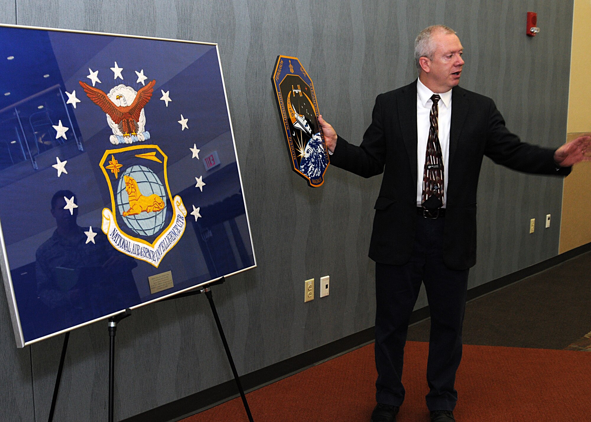 NASIC Historian, Mr. Robert Young, discusses hanging the framed flag on NASIC’s walls.  The flag flew over 6 million miles aboard the NASA Space Shuttle Endeavour to the International Space Station. (Photo courtesy of U.S. Air Force)