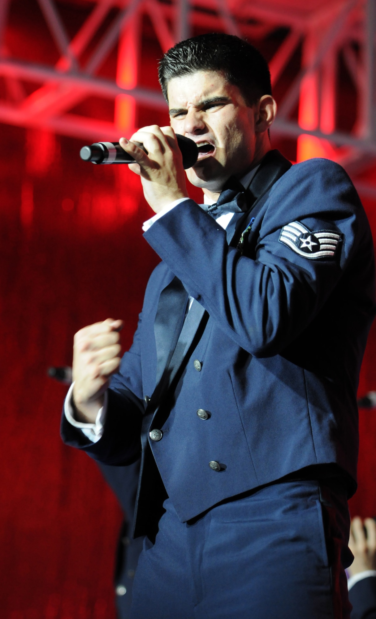 Staff Sgt. Robert Kalert, Tops in Blue vocalist, belts out Lee Greenwood’s “Proud to be an American” during the group’s July 4 performance at RAF Feltwell.  The song is Tops in Blue’s signature performance, which they sing at the finale of each show.  (U.S. Air Force photo by Staff Sgt. Austin M. May)