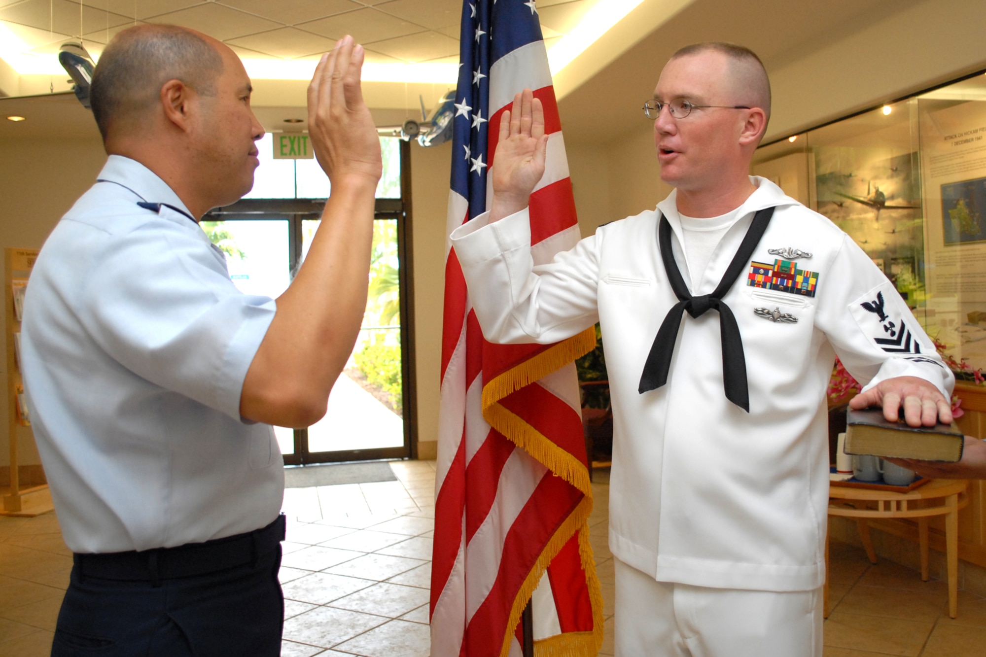HICKAM AIR FORCE BASE, Hawaii -- Col. Giovanni Tuck, 15th Airlift Wing commander, reenlists U.S. Navy Petty Officer 1st Class Jarrod A. Hickam, a submarine machinist?s mate aboard the USS Buffalo (SSN 715), during a ceremony in the headquarters building June 30. While in Pearl Harbor, Petty Officer Hickam wanted to have the commander of the base bearing his family?s namesake reenlist him. Petty Officer Hickam is the great-great-nephew Lt. Col. Horace Hickam. Following orders published by Gen. Douglas MacArthur, War Department Chief of Staff, a new flying field on the island of Oahu was dedicated and named "Hickam Field" May 31, 1935. Petty Officer Hickam is one of three petty officer first classes leading the auxiliary division and serves as the ship?s assistant quality assurance officer.  (U.S. Air Force photo by Staff Sgt. Mike Meares)