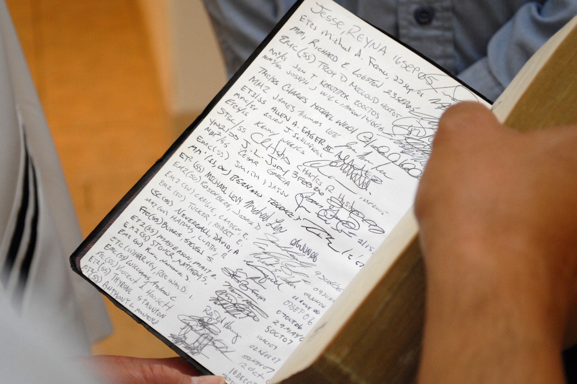 HICKAM AIR FORCE BASE, Hawaii -- The Holy Bible signed by the Sailors of the USS Buffalo (SSN 715) is shown to Col. Giovanni Tuck, 15th Airlift Wing commander, by U.S. Navy Petty Officer 1st Class Jarrod A. Hickam, a submarine machinist?s mate aboard the USS Buffalo (SSN 715), before a reenlistment ceremony in the headquarters building June 30. While in Pearl Harbor, Petty Officer Hickam wanted to have the commander of the base bearing his family?s namesake reenlist him. Petty Officer Hickam is the great-great-nephew Lt. Col. Horace Hickam. Following orders published by Gen. Douglas MacArthur, War Department Chief of Staff, a new flying field on the island of Oahu was dedicated and named "Hickam Field" May 31, 1935. Petty Officer Hickam is one of three petty officer first classes leading the auxiliary division and serves as the ship?s assistant quality assurance officer.  (U.S. Air Force photo by Staff Sgt. Mike Meares)