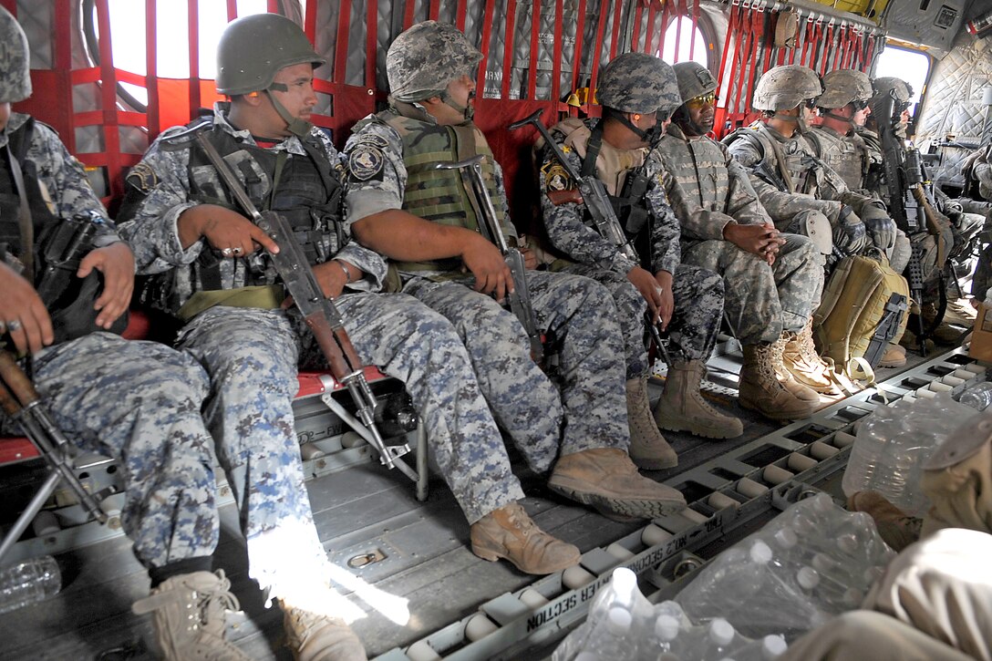 U.S. Army soldiers and Iraqi national policemen sit inside a CH-47 Chinook helicopter flying toward the objective during a joint air assault operation planned and led by the Iraqi army and police in the Ma'dain area east of Baghdad, Iraq, June 26, 2009.