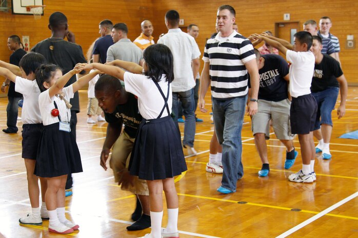 Marines and family members with Marine Wing Support Squadron 171 play a round of London Brige with the children of Kono Elementrary School during a cultural exchange hosted by the school July 7. The visit gave the Marines and children a better appreciation of each others culture through games and conversation.