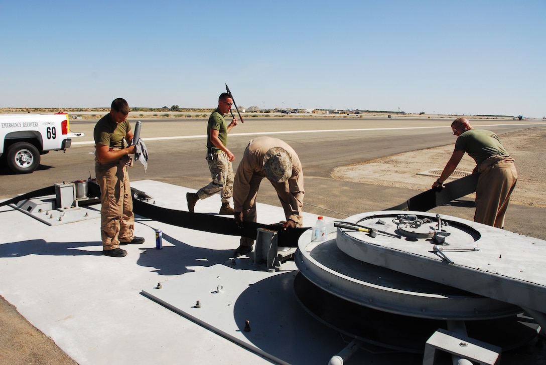 Emergency aircraft recovery crewmen Lance Cpl. Josh Kidwell, left, Lance Cpl. Nick Gohl, Sgt. William Seldon and Lance Cpl. Tony Eck repair one of four sets of arresting gear on the flight line at the Marine Corps Air Station in Yuma, Ariz., July 7, 2009. The recovery crew repaired a gear that was out of operation for more than two years. The device uses a heavy steel cable and heavy nylon tapes to rapidly decelerate landing aircraft in an emergency, much like the arresting gear on an aircraft carrier.
