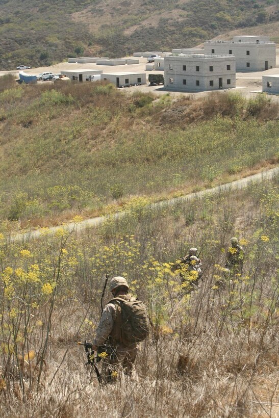 Marines with Company F, Battalion Landing Team 2/4, begin entering a simulated combat town after providing support by fire during a motorized raid here July 7. The raid force floated to shore from USS Cleveland using landing craft units, and took trucks and Humvees from the beach to the objective site. BLT 2/4 is preparing to deploy with the 11th Marine Expeditionary Unit later this year.