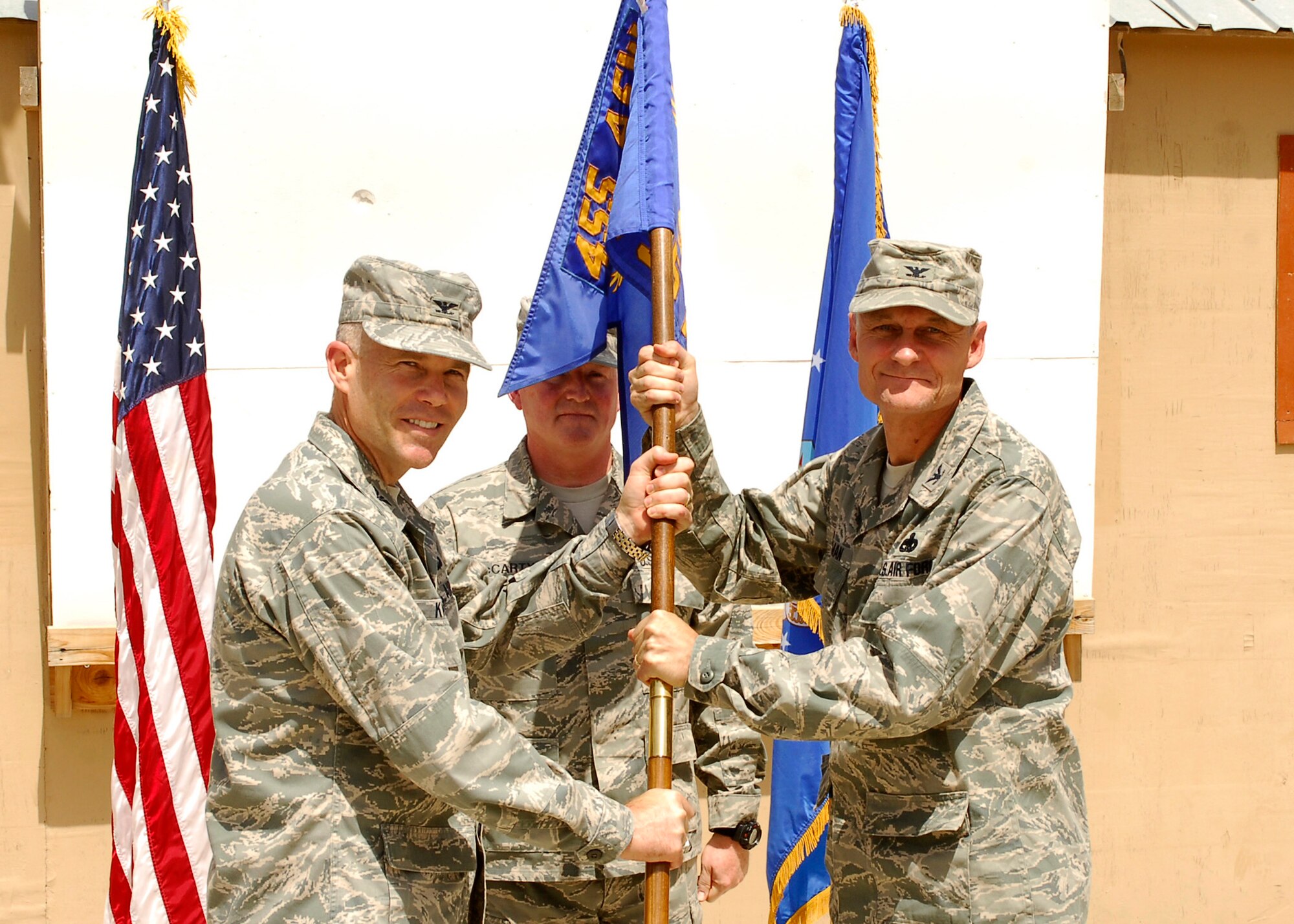 BAGRAM AIR FIELD, Afghanistan - Col. Steven Kwast (left), 455th Air Expeditionary Wing commander, hands the guidon to Col. James Meersman, who takes command of the 755th Air Expeditionary Group during an assumption of command ceremony, here July 6. (U.S. Air Force photo/Senior Airman Felicia Juenke)
