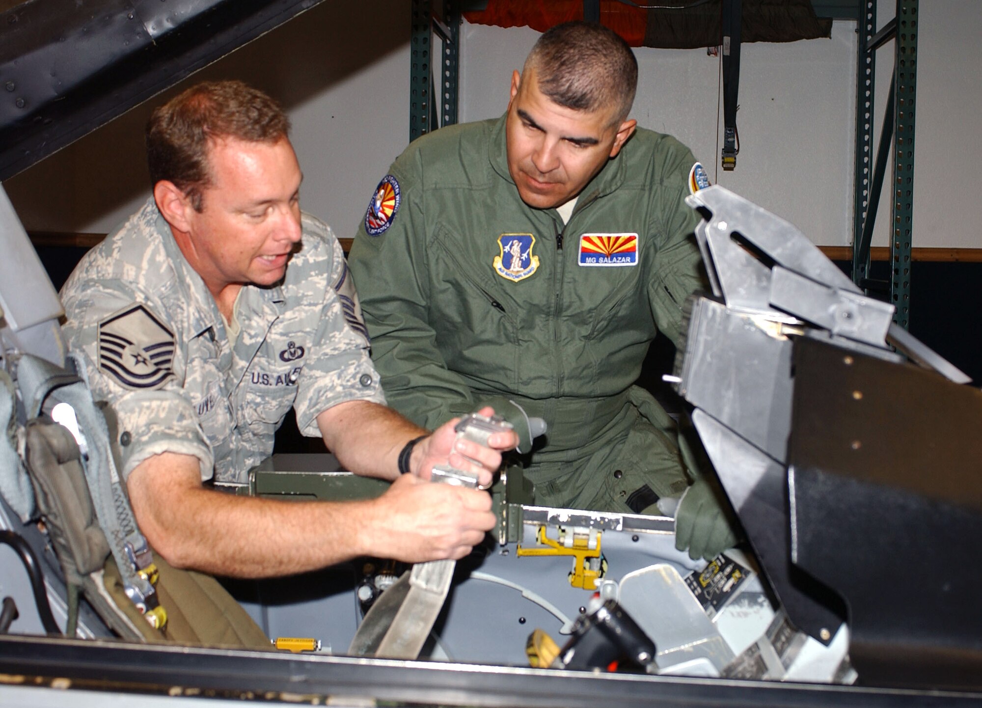 Army Maj. Gen. Hugo E. Salazar (right), Adjutant General and Commanding General of the Arizona National Guard, gets F-16 egress training from Master Sgt. Don Lauver at the 162nd Fighter Wing before his flight on July 7. Egress training teaches pilots and guest riders flight safety procedures for the high-performance jet. The experience was instrumental in familiarizing General Salazar with the wing's full-time mission to train U.S. and partner nation fighter pilots. (Air National Guard photo by Staff Sgt. Sarah Elliott)