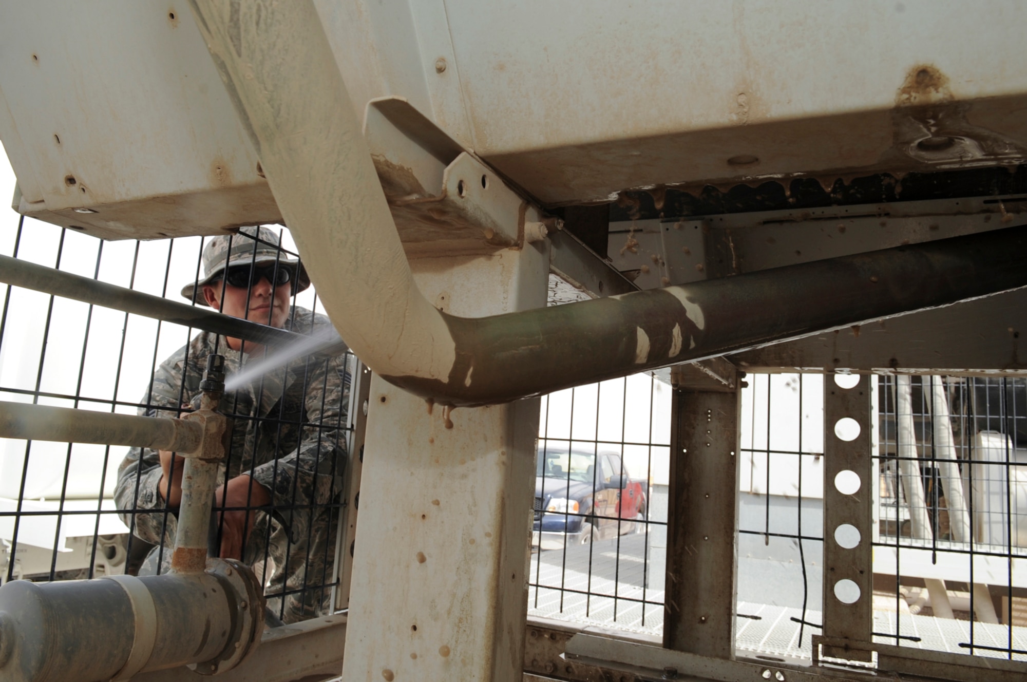 Senior Airman Domenic Trolla, 379th Expeditionary Civil Engineer Squadron heating, ventilation, air-conditioning and refrigeration technician, sprays built-up dirt off the air filters July 2 on a chiller that provides cool air to the Combined Air Operations Center at this air base in Southwest Asia.  The chillers are cleaned weekly to ensure they operate properly. Airman Trolla is native of Ironwood, Mich., and is deployed from Luke Air Force Base, Ariz.  (U.S. Air Force photo/Staff Sgt. Joshua Garcia)