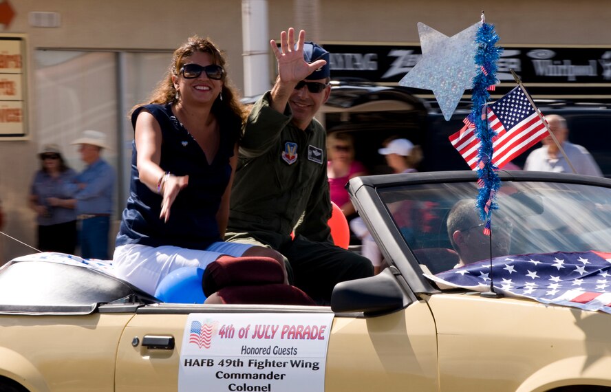 Honored guests, 49th Fighter Wing commander from Holloman Air Force Base, N.M., Col. Jeffrey Harrigian and his wife Kathy Harrigian, wave to onlookers during the city of Alamogordo, N.M., 4th of July Parade. (U.S. Air Force Photographer TSgt Alan Port Released)