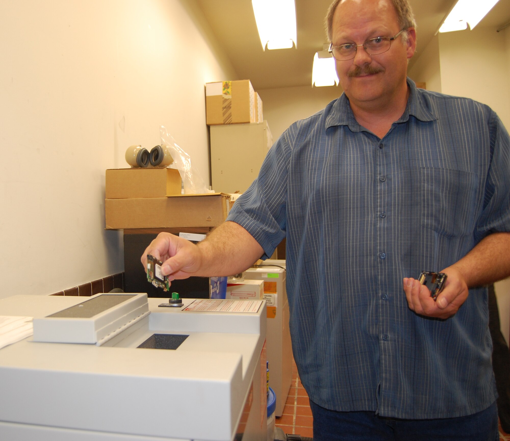 Wesley Speth, 341st Missile Wing information assurance analyst, gets ready to drop a piece of a cell phone into a disintegrator. The phone was destroyed because it was used improperly. According to Air Force Systems Security Instruction 8502, the use of privately-owned information systems to process or store critical unclassified information and personally identifiable information is not allowed. Privately-owned information systems contaminated with these types of information will be confiscated and sanitized according to directives. In this case, the only means of sanitation was destruction.