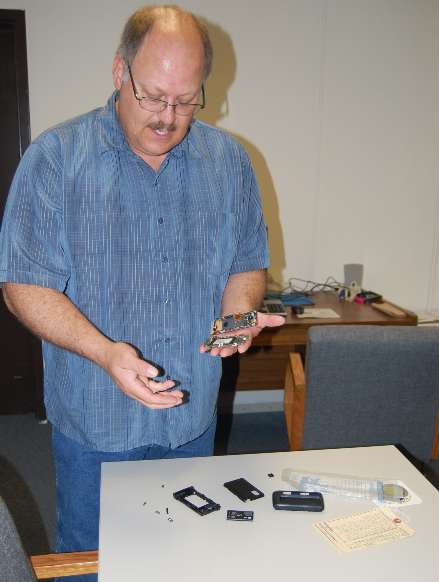 Wesley Speth, 341st Missile Wing information assurance analyst, displays a disassembled LG Dare VX9000 cell phone he is preparing to shred. (U.S. Air Force photo/Valerie Mullett)