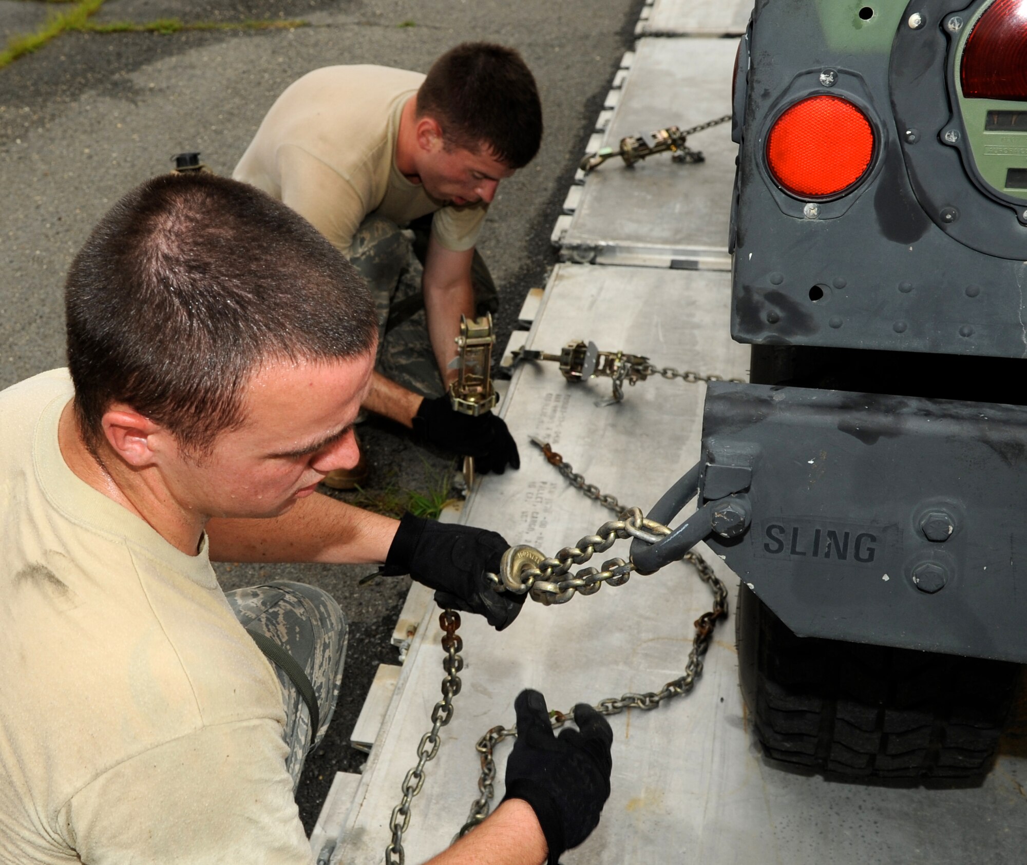 Staff Sgt. Timothy Hackett (front) and Staff Sgt. Jonathan Corwine (back), members of the 305th Aerial Port Squadron Rodeo Team, finish chaining down a humvee in preparation for air transport. This is just one of several tasks that had to be completed during a practice obstacle course designed to get the team ready for the annual Rodeo competition. (U.S. Air Force photo/Wayne Russell)
