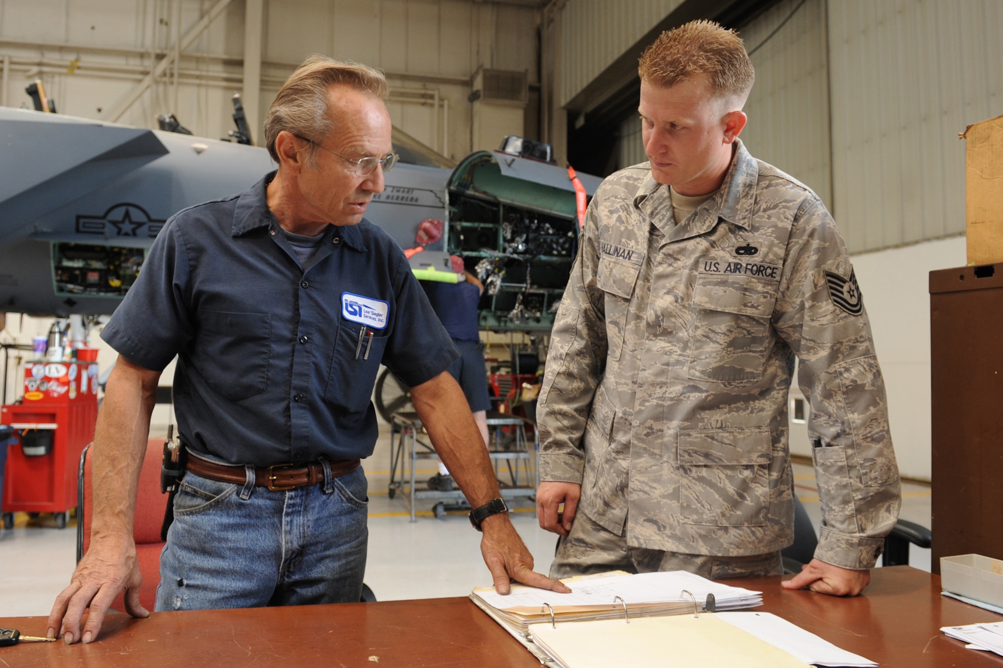Jim McKenna, a Boeing site supervisor, briefs Tech. Sgt. Ian Hallinan, 4th Equipment Maintenance Squadron, on an F-15E Strike Eagle wire routing at Seymour Johnson Air Force Base N.C., June 30, 2009. As the 4th Fighter Wing avionics manager, Sergeant Hallinan facilitates the work of aviation contractors, such as Boeing and Lear Siegler Inc., and ensures their avionics projects remain on schedule. (U.S. Air Force photo by Airman 1st Class Whitney S. Lambert)
