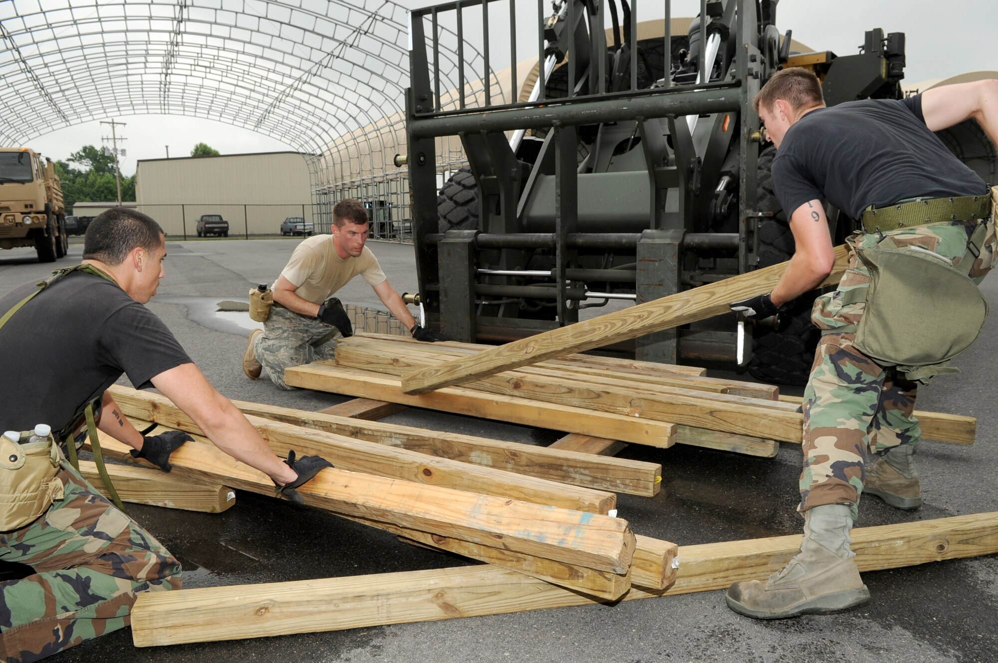 Working as a team, Airman 1st Class Marcus Rodriguez, Staff Sgt. Jonathan Corwine and Airman 1st Class Travis Rovelto finish stacking and aligning dunnage while their team members get a head start on the next 1/4-mile lap. All five members of the 305th Aerial Port Squadron Rodeo Team started this task of the obstacle course by moving all the dunnage together. (U.S. Air Force photo/Wayne Russell)
