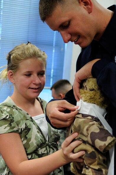 Bailey Reese, founder and president of the non-profit organization, Hero Hugs, and Staff Sgt. Michael Doss, United States Air Force Honor Guard Drill Team member, attach “Hero” with the highest level Drill Team ascot July 7 on Bolling Air Force Base D.C. Hero is the mascot for Hero Hugs and has toured Iraq and Afghanistan as a symbol of Bailey’s gratitude for military servicemembers.  (U.S. Air Force photo by Staff Sgt. Dan DeCook)