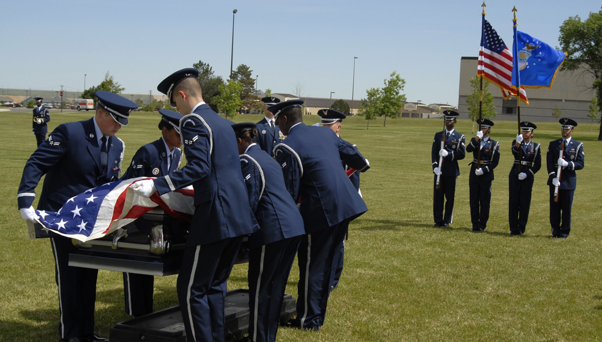 Members of the Malmstrom Air Force Base and Royal Air Force Mildenhall  honor guards lower a casket onto a mock-up during a full honors funeral demonstration June 24 at Medal of Honor Park. Mobile-training team instructors from the United States Air Force Honor Guard taught more than 20 ceremonial guardsmen uniform preparation and proper movements performed in pall bearing, firing party and the presentation of colors during a two-week course held here June 15 to 24. Ceremonial guardsmen were also required to recite the honor guard charge from memory to graduate. (U.S. Air Force photo/Beau Wade)