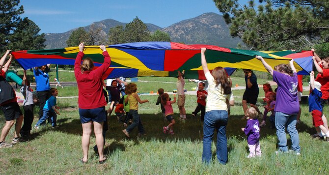 Children play under and around a parachute during Fit for the Future, Meet Me in the Park activities June 3. The program runs from 9 to 11 a.m. Tuesdays in Pine Valley and Thursdays in Douglass Valley through the end of July. (U.S. Air Force photo/Ann Patton)