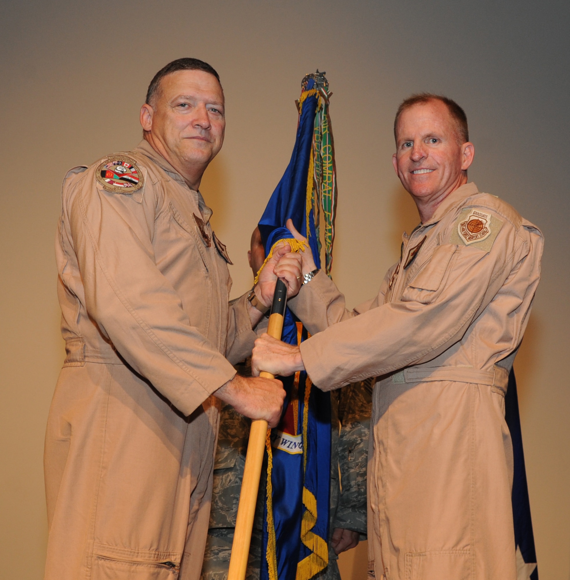(Left) Lt. Gen. Gary North, 9th Air Force and U.S. Air Forces Central commander, hands the 379th Air Expeditionary Wing guidon to Brig. Gen. Stephen Wilson, the incoming 379 AEW commander, during a change of command ceremony here, July 1. General Wilson was the Canadian North American Aerospace Defense Command Region deputy commander in Winnipeg, Canada. He is a B-1B Lancer pilot by trade. (US Air Force Photo/Staff Sgt. Joshua Garcia)