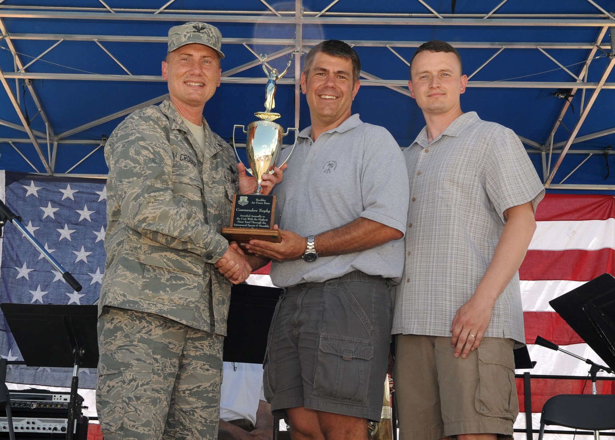 BUCKLEY AIR FORCE BASE, Colo. – Lt. Col. Delbert Jones, 460th Space Communications Squadron commander, and Master Sgt. Christopher Hart, 460th SCS satellite communication supervisor, accept the Commanders Cup from Col. Clint Crosier, 460th Space Wing commander, during the kick-off of Freedom Fest here, July 1.  The cup is given to the unit that accumulates the most points through the sports calendar year.  (U.S. Air Force photo by Senior Airman Randi Flaugh)