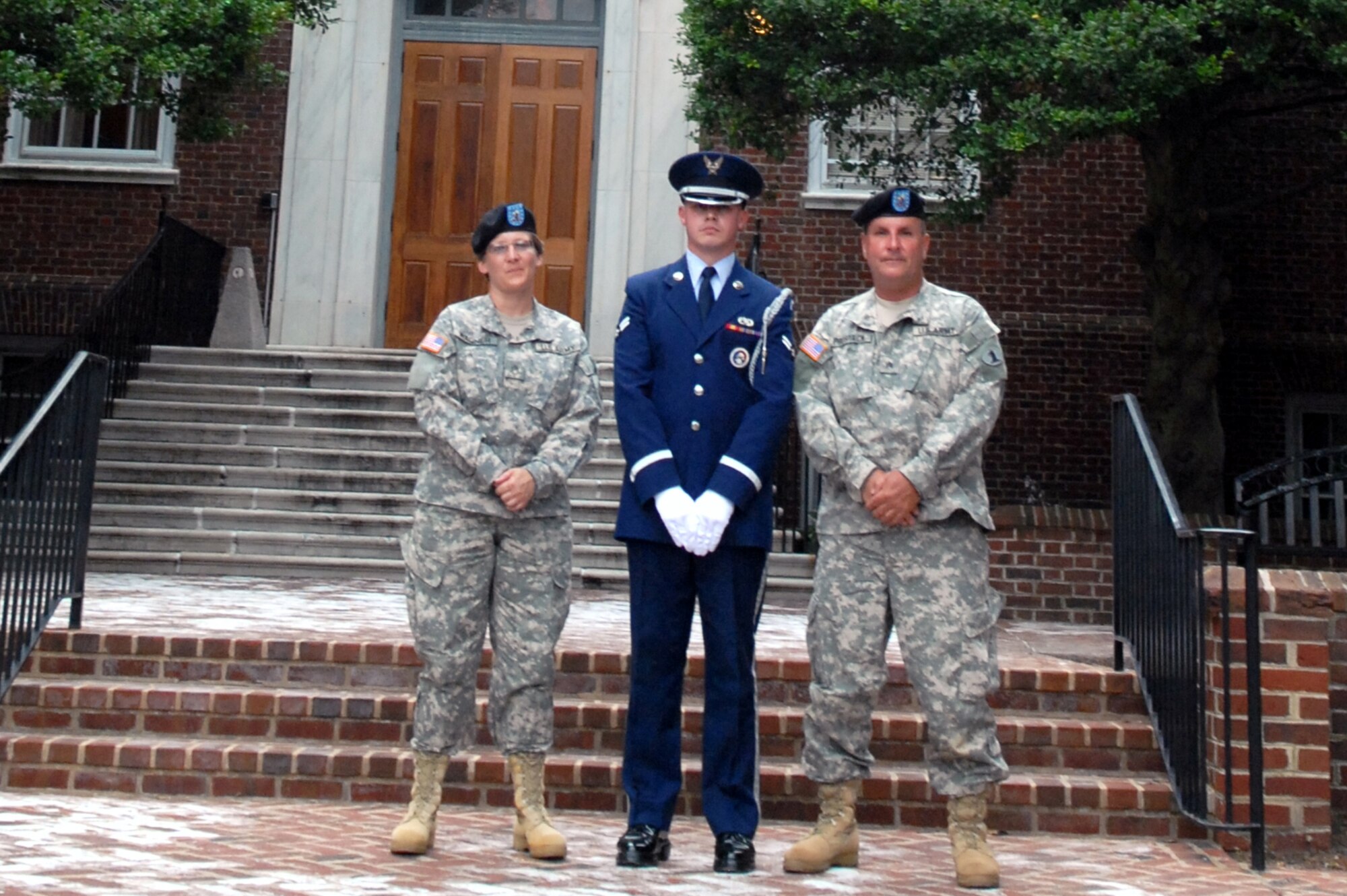 Army Staff Sgt. Mary Wagner, 287th Army Band from the Delaware National Guard member, Airman 1st Class Jonathon Zuraff, Dover Air Force Base Honor Guard member, and Army Sgt. Richard Prostack, 287th Army Band member convene under an American Flag in front of the Delaware State Capital Building in Dover. The three met briefly to discuss preparations relating to the Honor Guards role in posting the colors and kicking off the band?s evening selection of patriotic music. (U.S. Air Force photo/Tech. Sgt. Kevin Wallace)