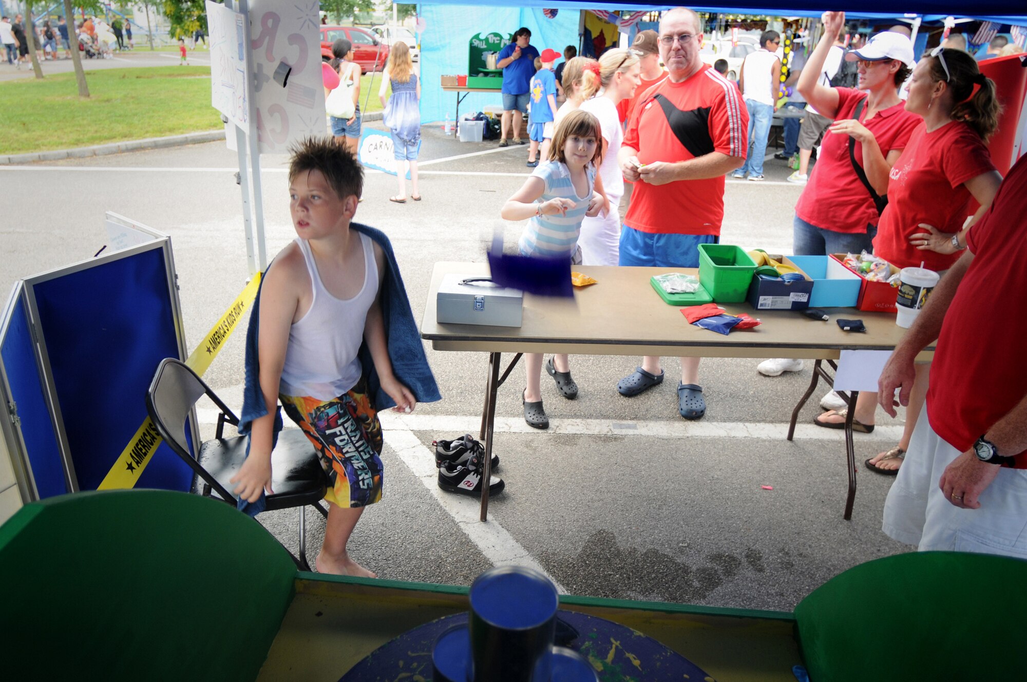 Kaitlyn Holloway (center), daughter of Dave Holloway, throws a sand bag at cans at one of the game booths here during the 4th of July Celebration.  The festivities consisted of various events throughout the day and concluded with a fireworks display at night commemorating 233 years of Independence. (U.S. Air Force photo/ Staff Sgt. Patrick Dixon)