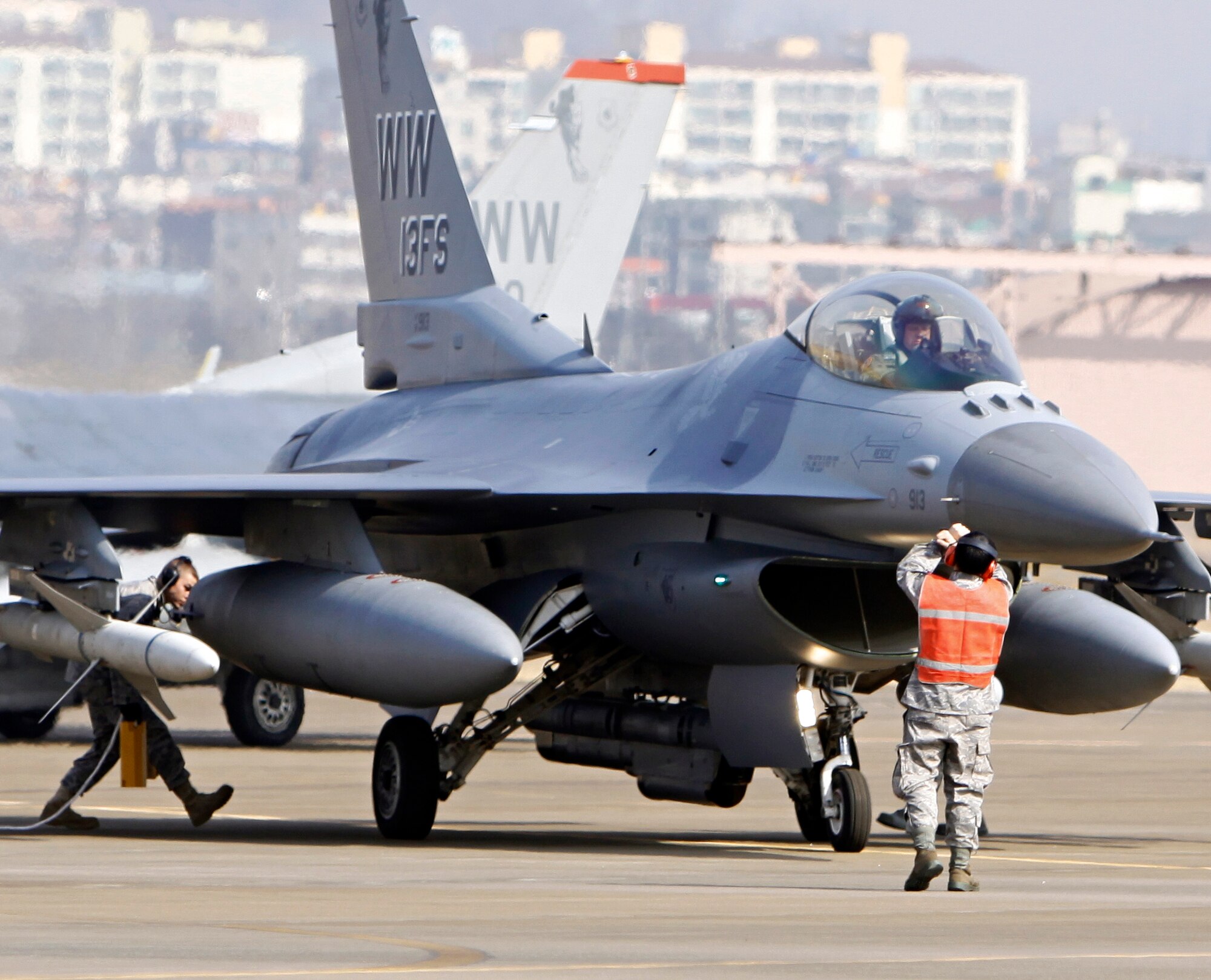 SUWON AIR BASE. Republic of Korea -- An F-16 Fighting Falcon is marshaled into its spot by two 13th Expeditionary Fighter Squadron ground crew members Feb. 23 at Suwon Air Base. Approximately 280 Airmen deployed to the R.O.K. as part of a theater security package. (Air Force photo/Senior Master Sgt. Wayne Cardwell) 