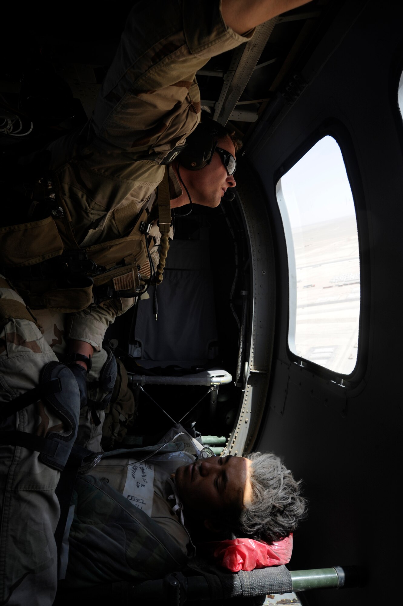 Inside of an HH-60G Pave Hawk, Senior Airman Clint Lentz, pararescueman, 129th Expeditionary Rescue Squadron watches for any potential dangers prior to landing June 26, 2009, Camp Bastion, Afghanistan. Airman Lentz and the rest of the crew are bringing an injured Afghan National Army Soldier to a hospital for further care.   (U.S. Air Force photo by Staff Sgt. Shawn Weismiller)