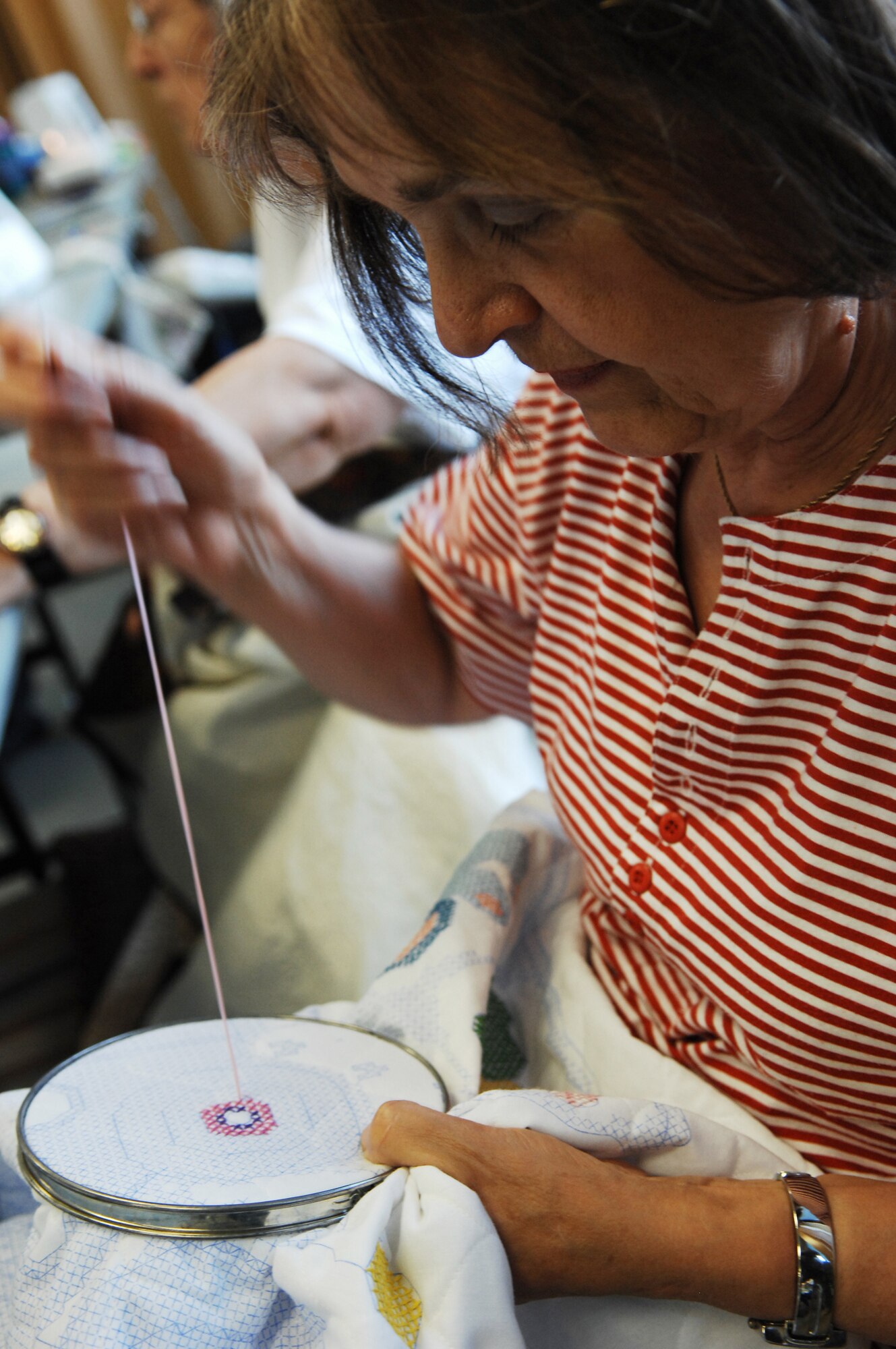 Ms. Bridget Nakata, member of the Rheinland-Pfalz Quilt Guild cross-stitches a baby crib cover for a family friend on June 26, 2009,  Ramstein Air Base, Germany. The quilt guild is a non-profit organization that gets together weekly to fellowship and sew. They also create Quilts of Valor for wounded warriors and Baby Love Quilts for babies in the neonatal intensive care unit at Landstuhl Regional Medical Center.  (U.S. Air Force photo by Tech. Sgt. Chenzira Mallory)