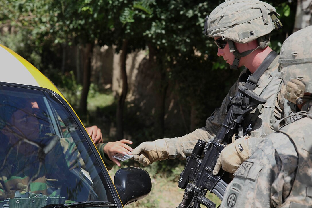 U.S. Army Sgt. Matthew Nesheim checks identification at a traffic control point near Calehnasno village in the Bagram district of Parwan province, Afghanistan, July 4, 2009. Nesheim is assigned to the 82nd Airborne Division's Company B, Special Troops Battalion.
