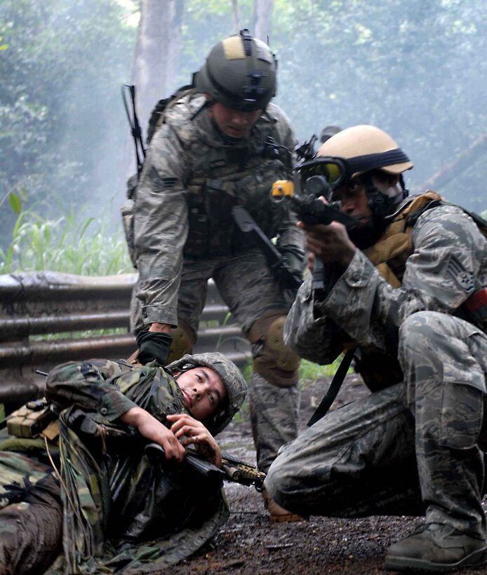U.S. Air Force Staff Sgt. Anthony Stewart provides small arms fire cover for Senior Airman Robert Gains while he drags Senior Airman Christopher Lee, a “casualty,” to safety, during a training exercise on Wheeler Army Air Field’s East Range, Hawaii. June 24, 2009.