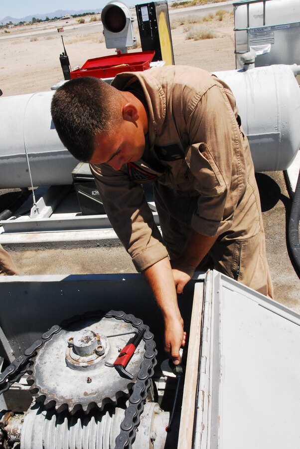 Emergency aircraft recovery crewman Lance Cpl. Josh Kidwell adds lubricant to the engine of one of four sets of arresting gear on the flight line at the Marine Corps Air Station in Yuma, Ariz., July 8, 2009. The recovery crew repaired a set of gear that was out of operation for more than two years. The device uses a heavy steel cable and heavy nylon tapes to rapidly decelerate landing aircraft in an emergency, much like the arresting gear on an aircraft carrier.