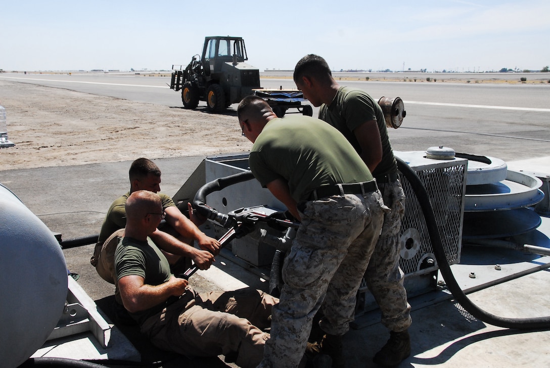 Emergency aircraft recovery crewmen strain to remove a plug on the engine of one of four sets of arresting gear on the flight line at the Marine Corps Air Station in Yuma, Ariz., July 8, 2009. The recovery crew repaired a set of gear that was out of operation for more than two years. The device uses a heavy steel cable and heavy nylon tapes to rapidly decelerate landing aircraft in an emergency, much like the arresting gear on an aircraft carrier.