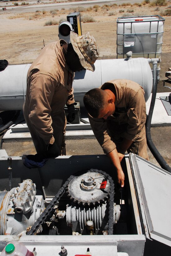Emergency aircraft recovery crew leader Sgt. William Seldon and crewman Lance Cpl. Josh Kidwell check the lubrication on one of four sets of arresting gear on the flight line at the Marine Corps Air Station in Yuma, Ariz., July 8, 2009. The recovery crew repaired a set of gear that was out of operation for more than two years. The device uses a heavy steel cable and heavy nylon tapes to rapidly decelerate landing aircraft in an emergency, much like the arresting gear on an aircraft carrier.