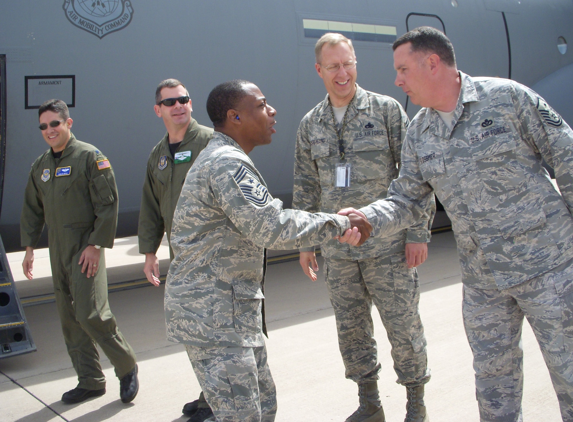 Chief Master Sgt. Anthony Brinkley, 19th Airlift Wing command chief (center), shakes hands with Master Sgt. Chris Vossmer July 9 after landing at Peterson Air Force Base, Colo. Chief Brinkley, together with 19th AW commander Col. Gregory Otey, briefly visited the Air Force Reserve's 302nd Airlift Wing during a stopover at the base. The 302nd AW is taking on an active association mission in the fall, integrating Active Duty Airmen into the AF Reserve mission at Peterson. Behind Chief Brinkley is (right to left) Chief Master Sgt. James Westerlund, 302nd AW command chief; Lt. Col. Brad Ross, 731st Airlift Squadron pilot; and Lt. Col. Carlos Ortiz, 19th AW, Detachment 3 commander. Sergeant Vossmer is the detachment first sergeant. The 19th AW is based at Little Rock AFB, Ark. (U.S. Air Force photo/Staff Sgt. Stephen J. Collier)