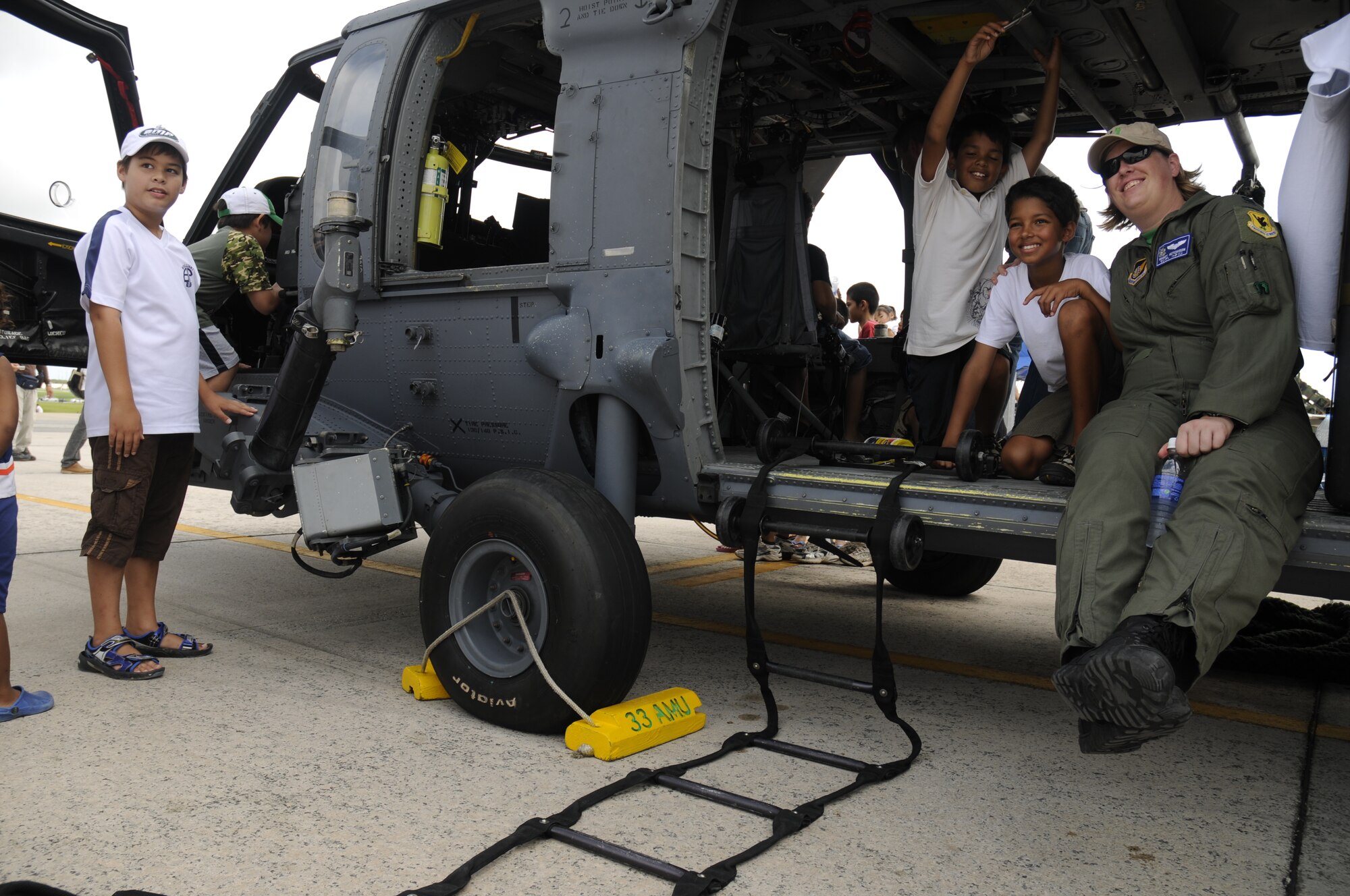 Capt. Amanda Hutchison, from the 18th Wing Safety Office, poses with children for a photo on an HH-60 helicopter during Americafest 09' at Kadena Air Base, Japan, July 4. (U.S. Air Force Photo/Airman 1st Class Chad Warren)         