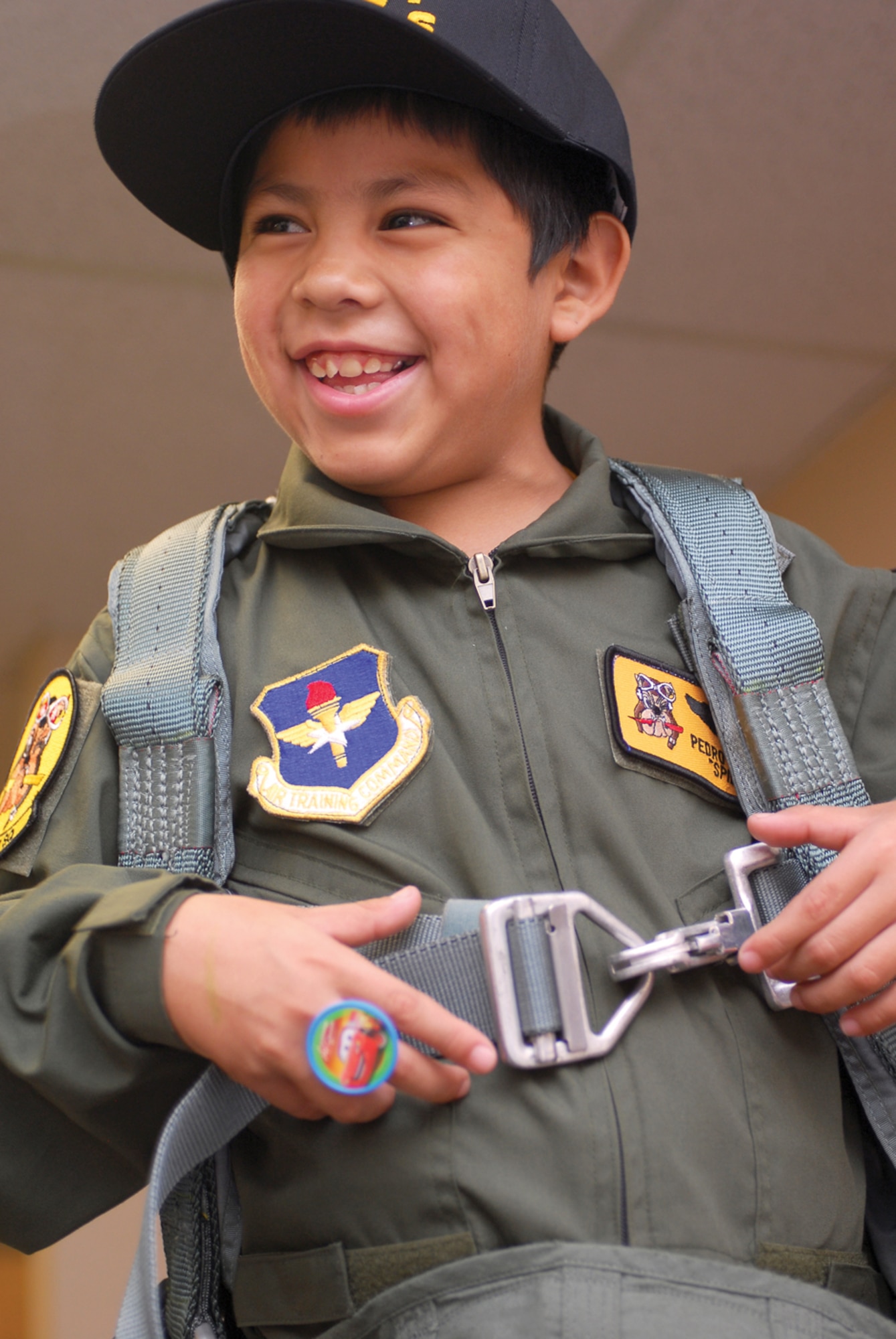 Pilot-for-a-day, Pedro “Spidey” Castro, 10, tries on a harness in the Life Support section of the 61st Fighter Squadron during his visit to Luke Air Force Base June 29. (U.S. Air Force photo/ Senior Airman Tracie Forte)