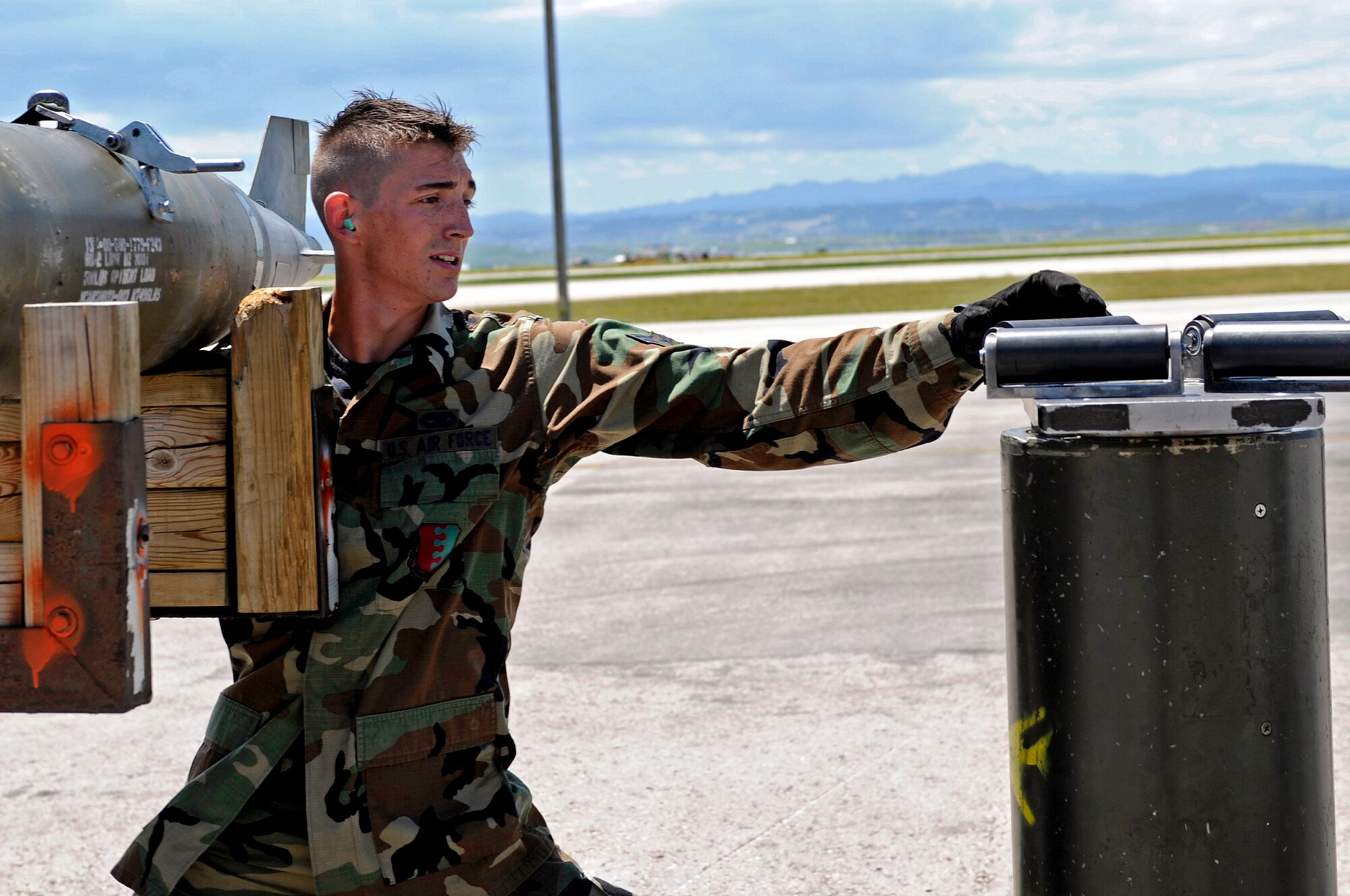 Airman 1st Class Anthony Floyd, 28th Maintenance Squadron weapons load crew member, positions himself to place a MK-82 weapon on a jammer during a load competition here, July 7. The competition featured two four-man teams from the 34th and 37th Bomb Squadron Aircraft Maintenance Units. The 34 BS team won the competition. (U.S. Air Force photo/Airman 1st Class Matthew Flynn)
