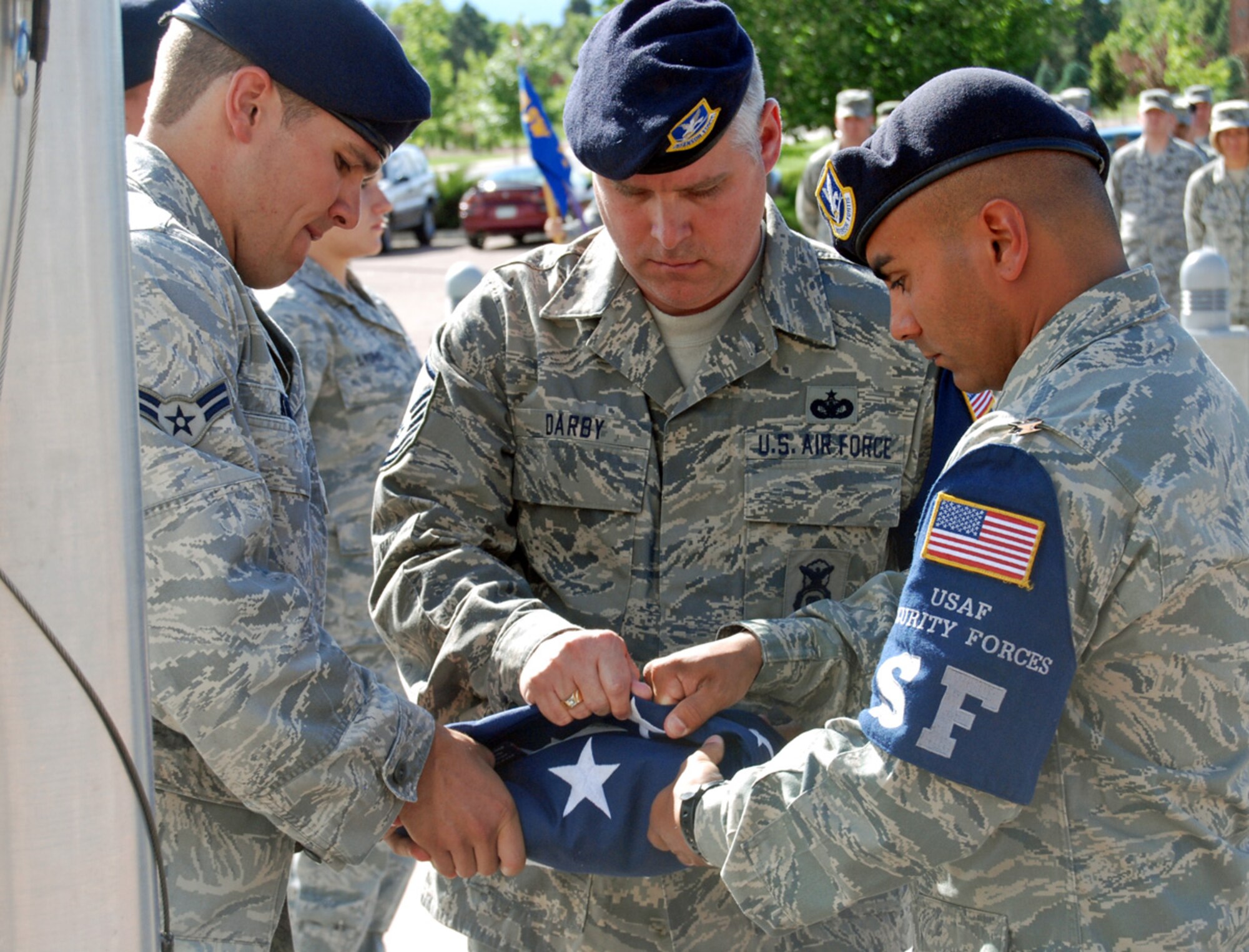 Master Sgt. Tristum Darby (center), 21st Security Forces Squadron, and two 21st SFS Airmen, fold the flag during retreat at the 21st Space Wing Headquarters building flagpole June 30. Col. Emily Buckman, 21st Mission Support Group commander led the Retreat formation which was comprised of 40 local Airmen. As directed by Col. Jay Raymond, 21st SW commander, each Peterson group or squadron will be responsible for conducting Retreat once a month on a rotating basis. (Air Force photo by Tech. Sgt. Ray Bowden) 