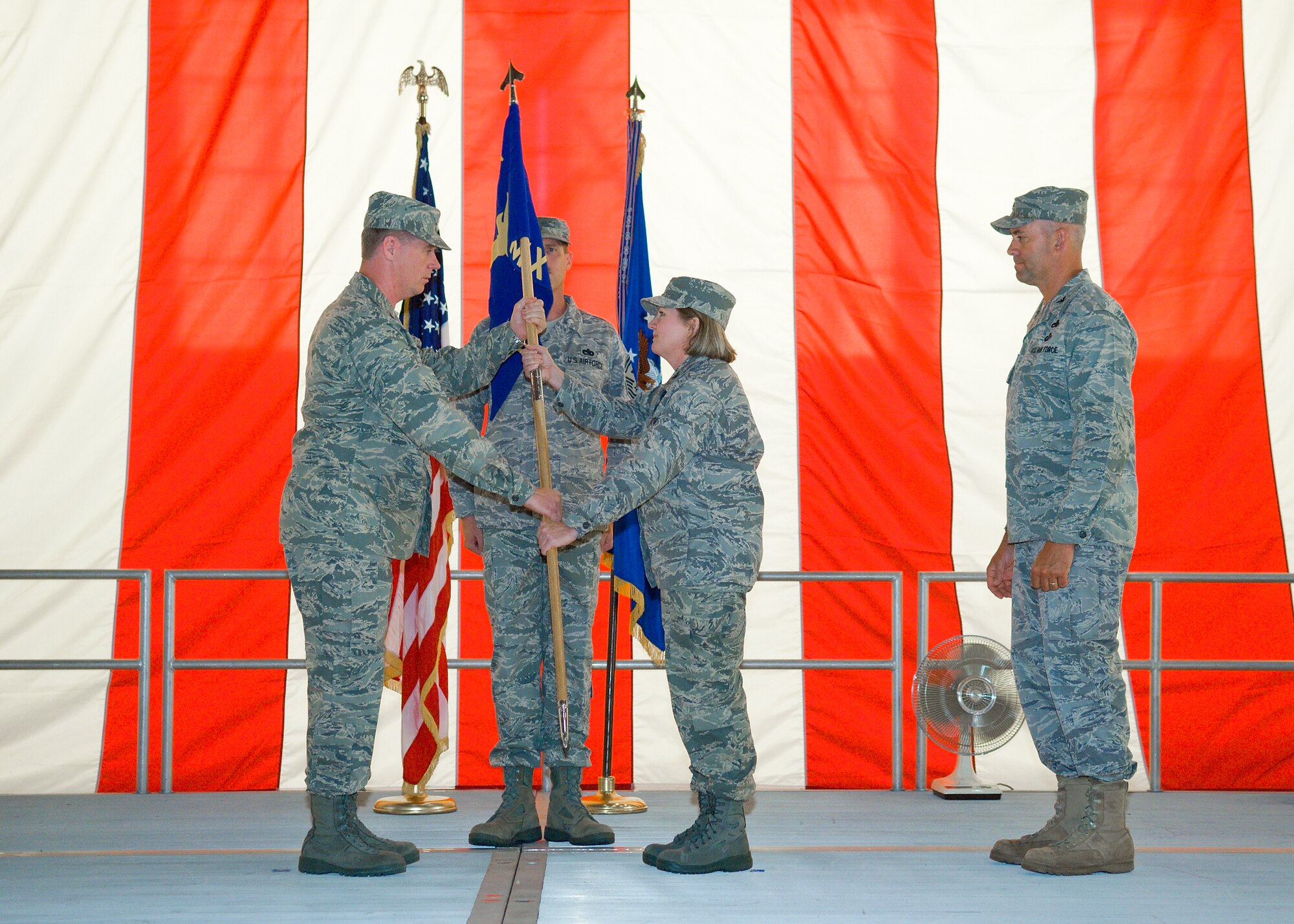 Col. William Thornton (left), 412th Test Wing commander, presents the 412th Maintenance Group guidon to Col. Mary Ann Behne as  she assumes command July 7 in Hangar 1600 at Edwards Air Force Base, Calif. (Air Force photo/Mike Cassidy)