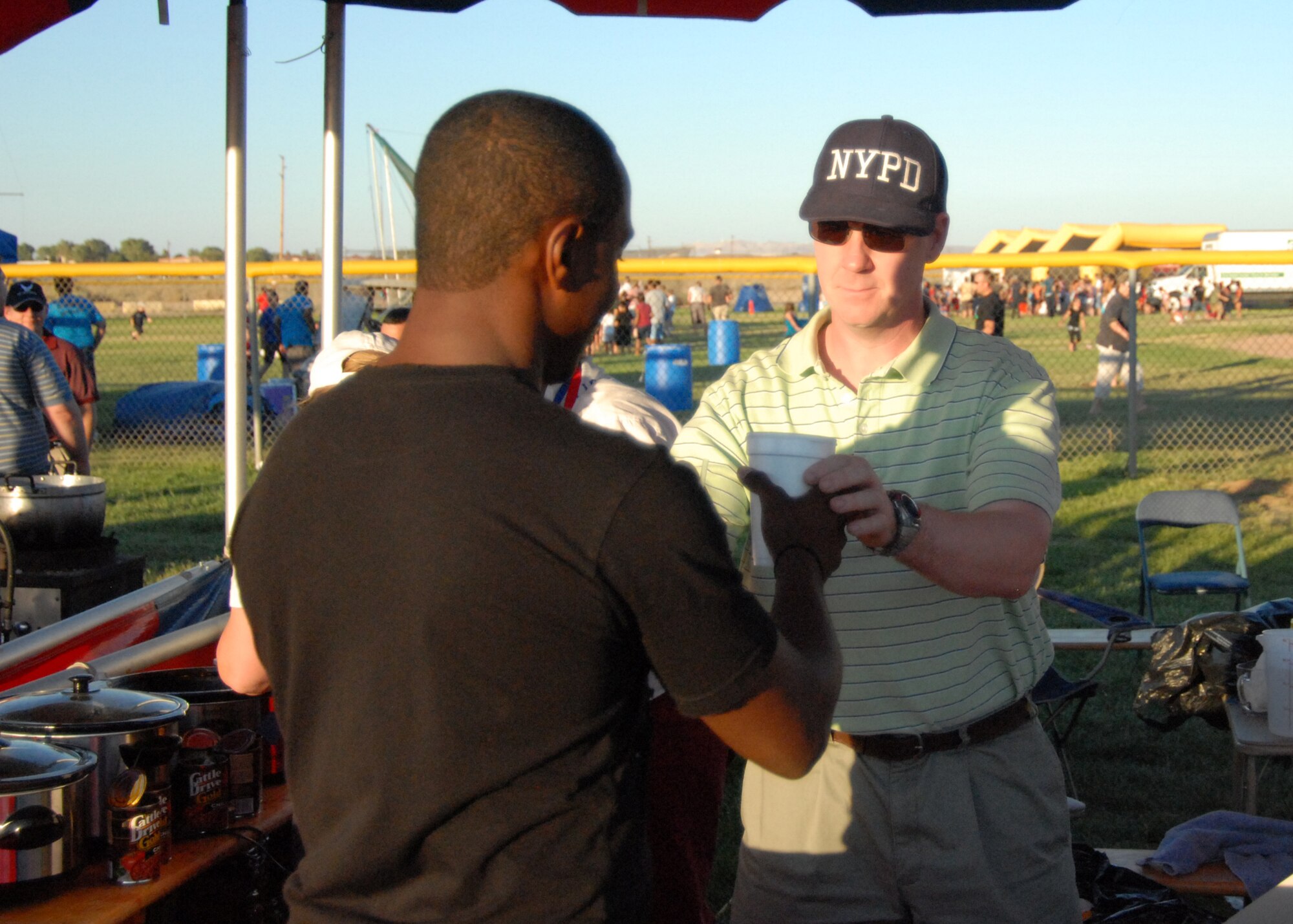 Col. William Thornton, 412th Test Wing commander, serves Airman 1st Class Devon Sumter, 95th Security Forces Squadron patrolman a drink during Summer Bash here July 4. Food and drink were sold by representitves from the base's private organizations. (Air Force photo/Airman 1st Class William O'Brien) 