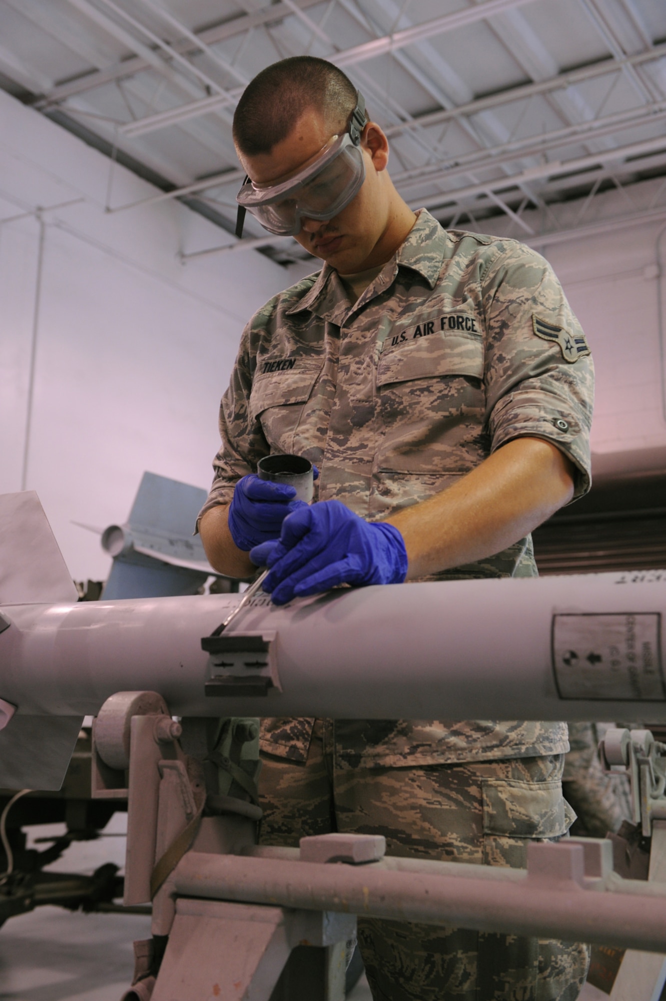 Airman 1st Class Bryan Tieken, 4th Equipment Maintenance Squadron munitions systems journeyman, paints a weapon's hanger on Seymour Johnson Air Force Base, N.C., July 7, 2009. The paint markings inform load crews whether or not the weapon can be placed on aircraft. Each missile has four hangers that to attach the missile to the aircraft. (U.S. Air Force photo by Airman 1st Class Whitney S. Lambert) 