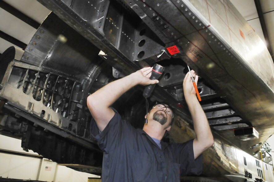 Steve Hartley, site manager, examines the underbelly of an F-15 prior to disassembly.  U. S. Air Force photo by Sue Sapp